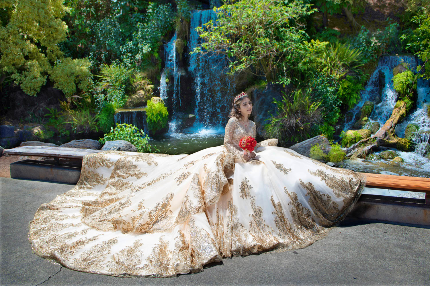 Quinceañera con vestido blanco y dorado frente a cascadas